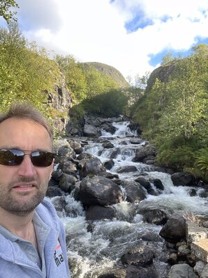 Paul is posing in front of the waterfall